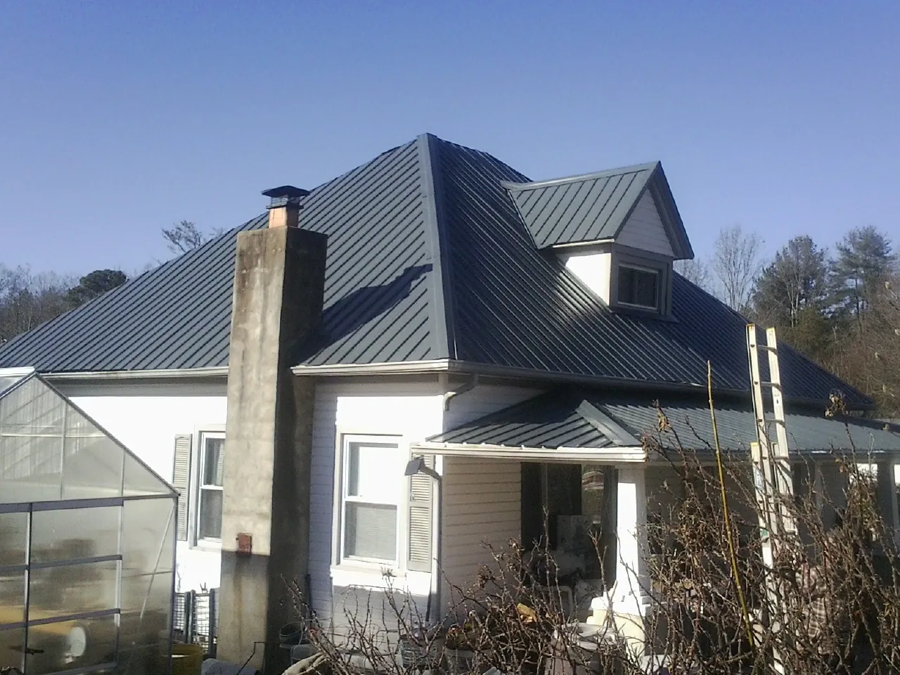 Dark blue standing seam metal roof on a white farmhouse with dormer — Slate & Tile Roof Repair by Roofing Brothers in Idaho City