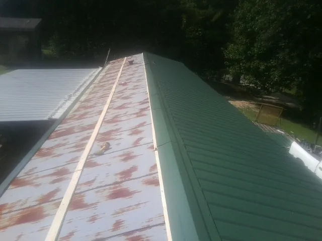 Old rusted panels beside newly installed green metal roofing — Wind Damage Roof Repair by Roofing Brothers in Idaho City