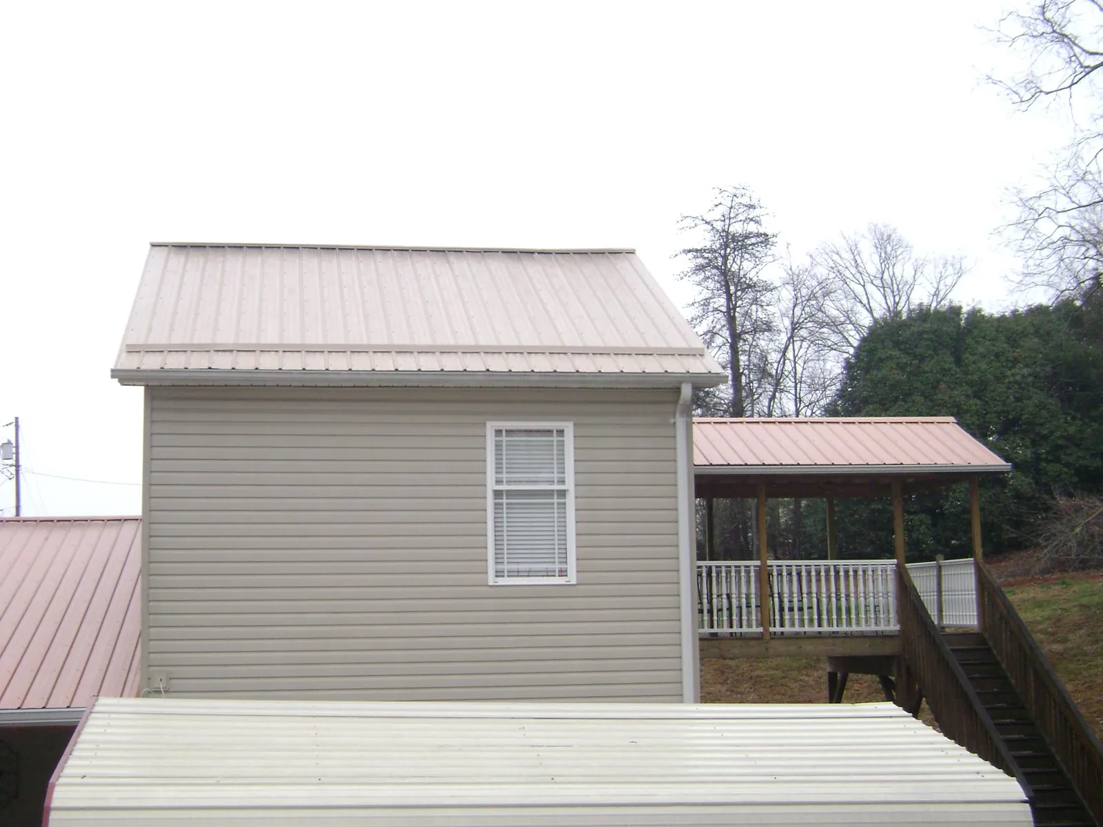 Tan metal roofs on a two story addition and attached porch, from a Roof Replacement job in Idaho City
