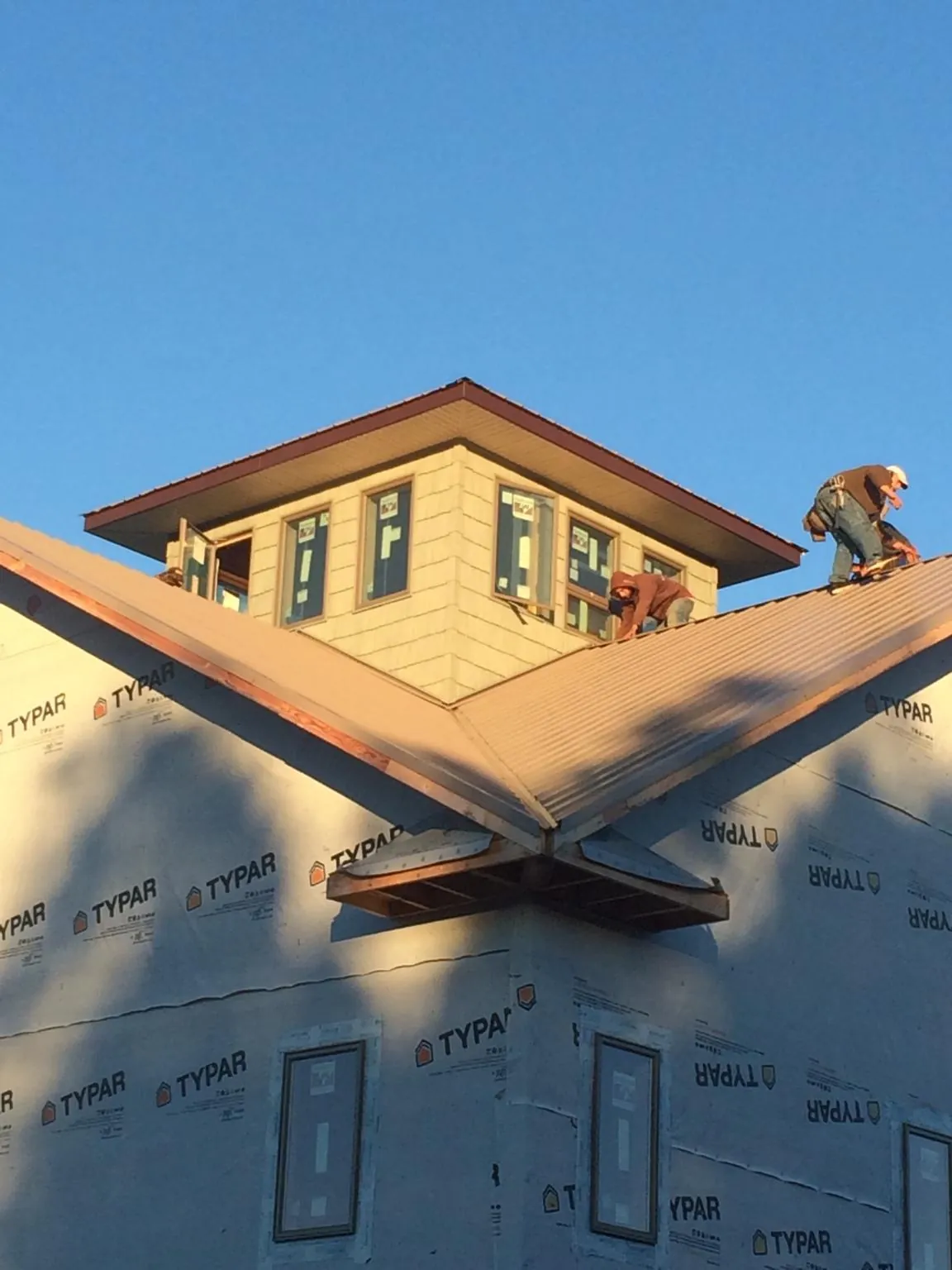 Roofers working around a rooftop cupola on a new metal roof at sunset — Roof Waterproofing in Idaho City by Roofing Brothers
